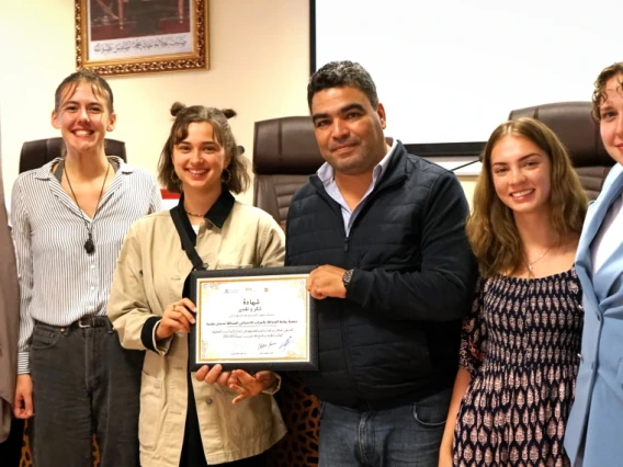 Six people stand together, two holding a certificate