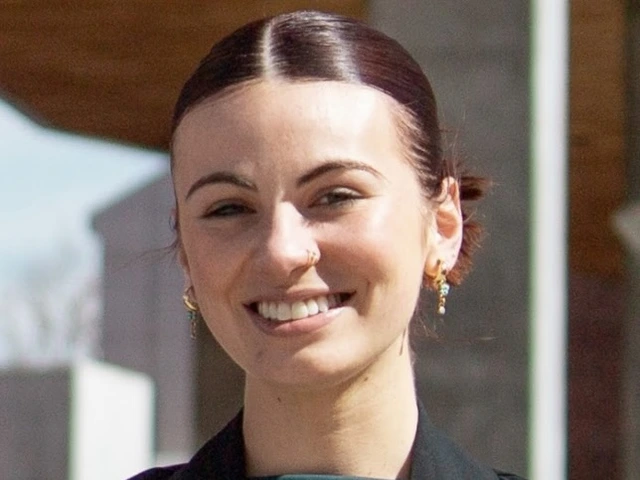 Woman with dark brown hair pulled back, wearing a green top and black jacket