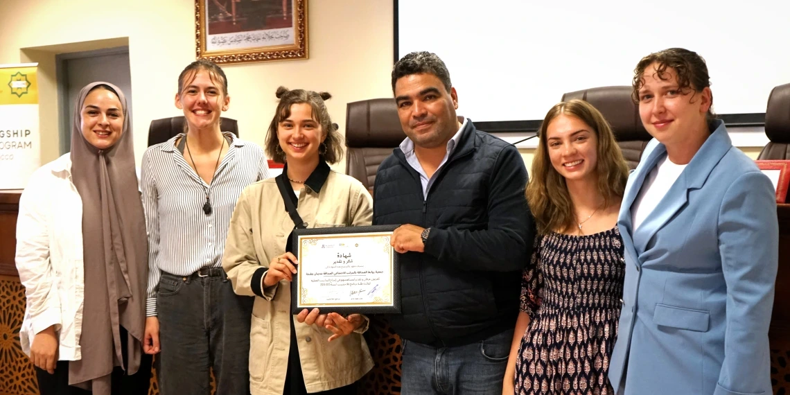 Six people stand together, two holding a certificate