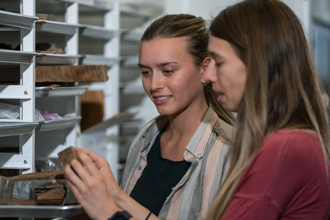 two young woman looking at tree ring samples