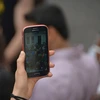 Hand holding a cell phone that is taking video of a crowd of people