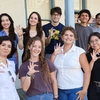 Nine students stand outside and show the sign for "Wildcats"