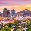 Tucson skyline at sunset, with the city’s buildings silhouetted in warm light and the iconic mountain in the background.
