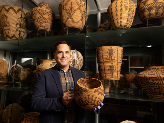 Edward Jolie holds a woven basket and stands in front of many more