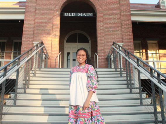 Shanae Dosela stands on the stairs of the Old Main building