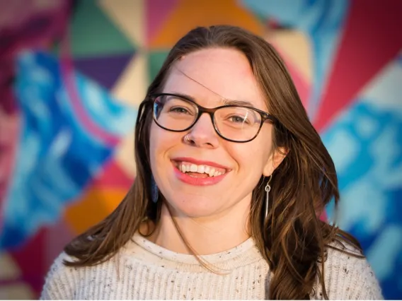 Melinda Englert smiles in front of a colorful background