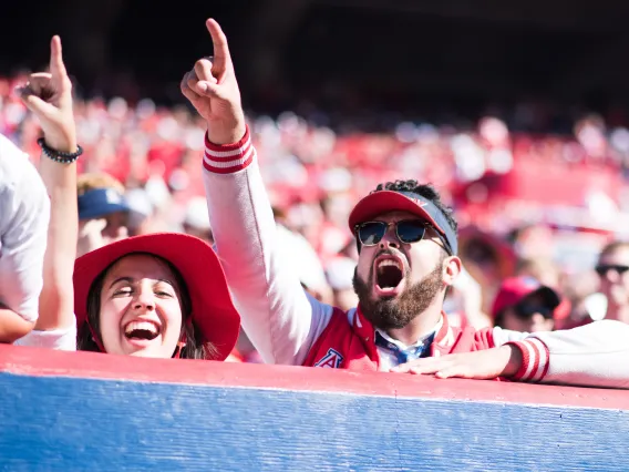 Students cheering over a wall