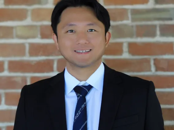 Hyeonchang "Kay" Gim smiling with brick wall background