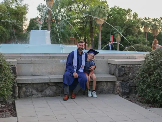 Man sitting in front of a fountain with his son 