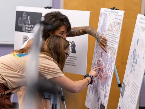 Two women bent over, looking and pointing at a map