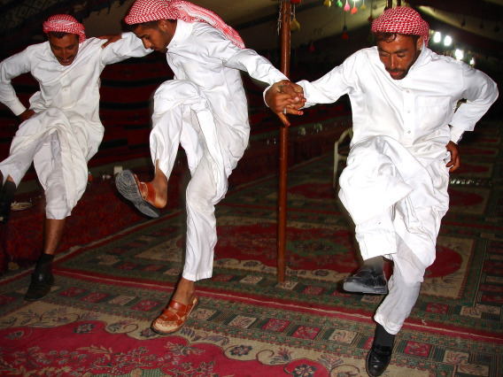 three Middle Eastern med in white clothes dancing