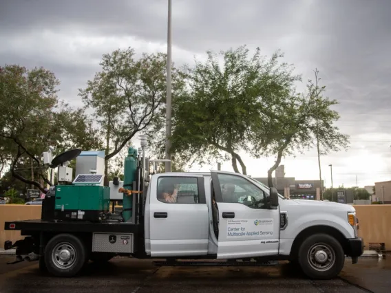 A utility-looking truck is parked outside under trees