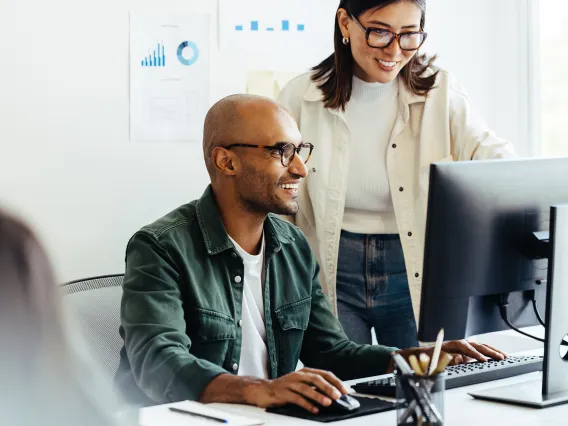 a man and a woman with glasses in front of a computer screen