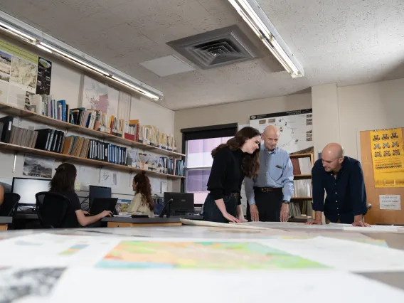 David Gilman Romano stands at a mapping table with two students