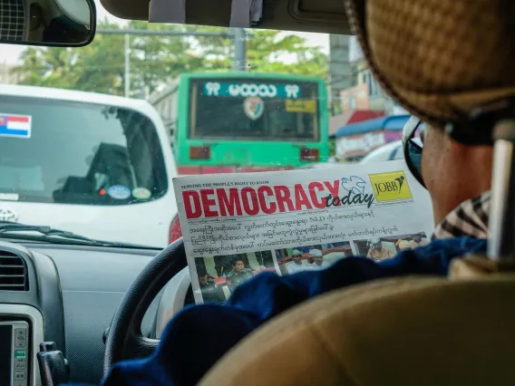 A person in a car reads a newspaper in a foreign language