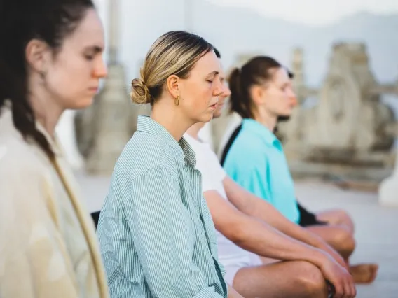 Women and men sitting outside meditating