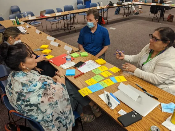 Men and women sit around a table covered in sticky notes