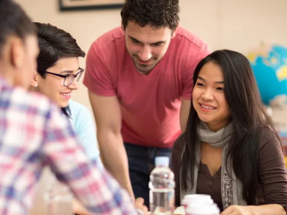 A group of students sit around a table, smiling