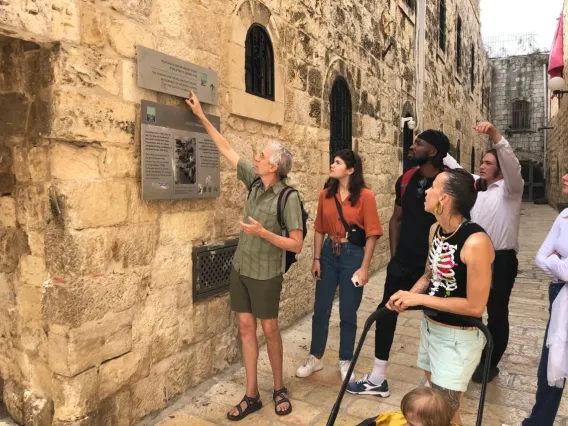 A professor points to a sign in front of a group of students in the old City of Jesursalem