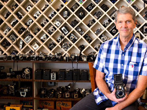 man posing with many cameras