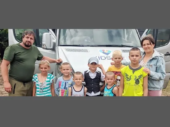 couple with seven children in front of car