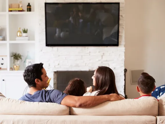 Latino family, father, mother and two children watching TV