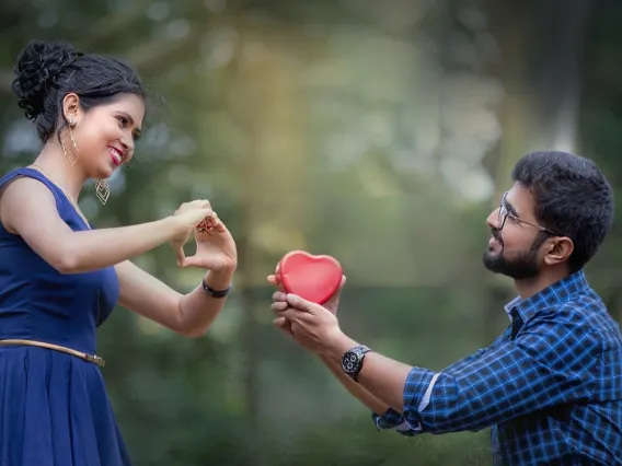 man handing red plastic heart to woman