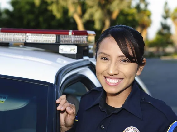 Police officer posing for photo next to a police car.