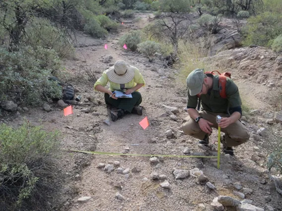 Two people record the physical attributes of a trail 