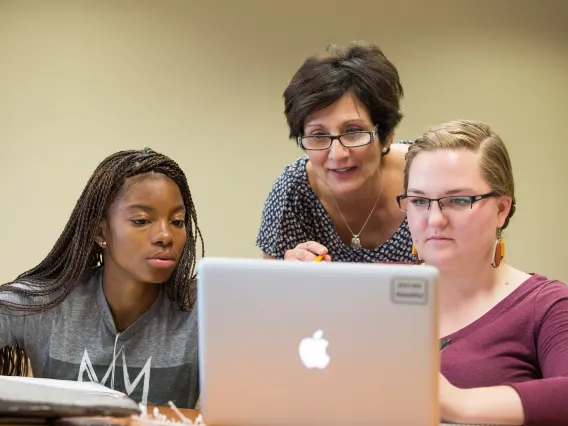 Professor and students working on laptop