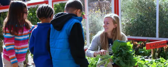 Photo of undergraduate working elementary students in school garden