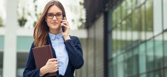 Intern with porfolio talking on cell phone outside of government buildiing