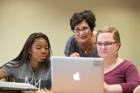 Professor and students working on laptop