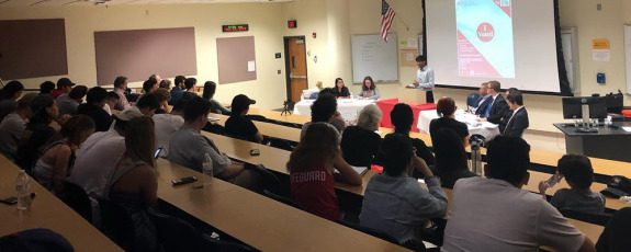 Student speaking in front of large audience at debate