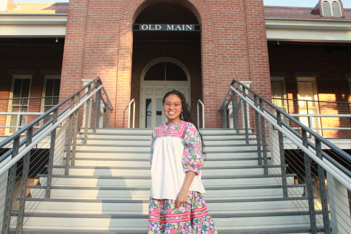 Shanae Dosela stands on the stairs of the Old Main building