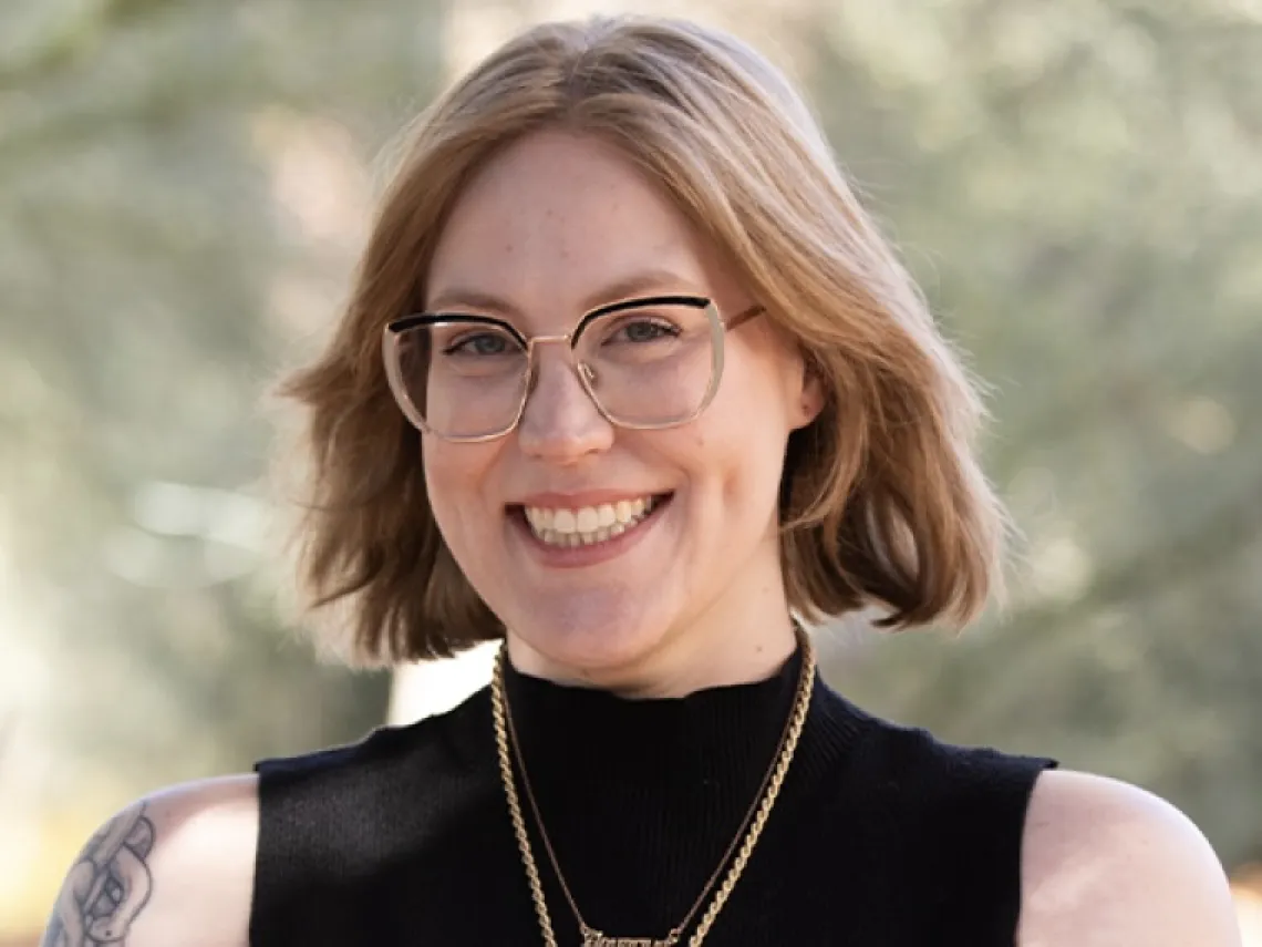 Woman with strawberry blonde hair, glasses and black shirt standing outside