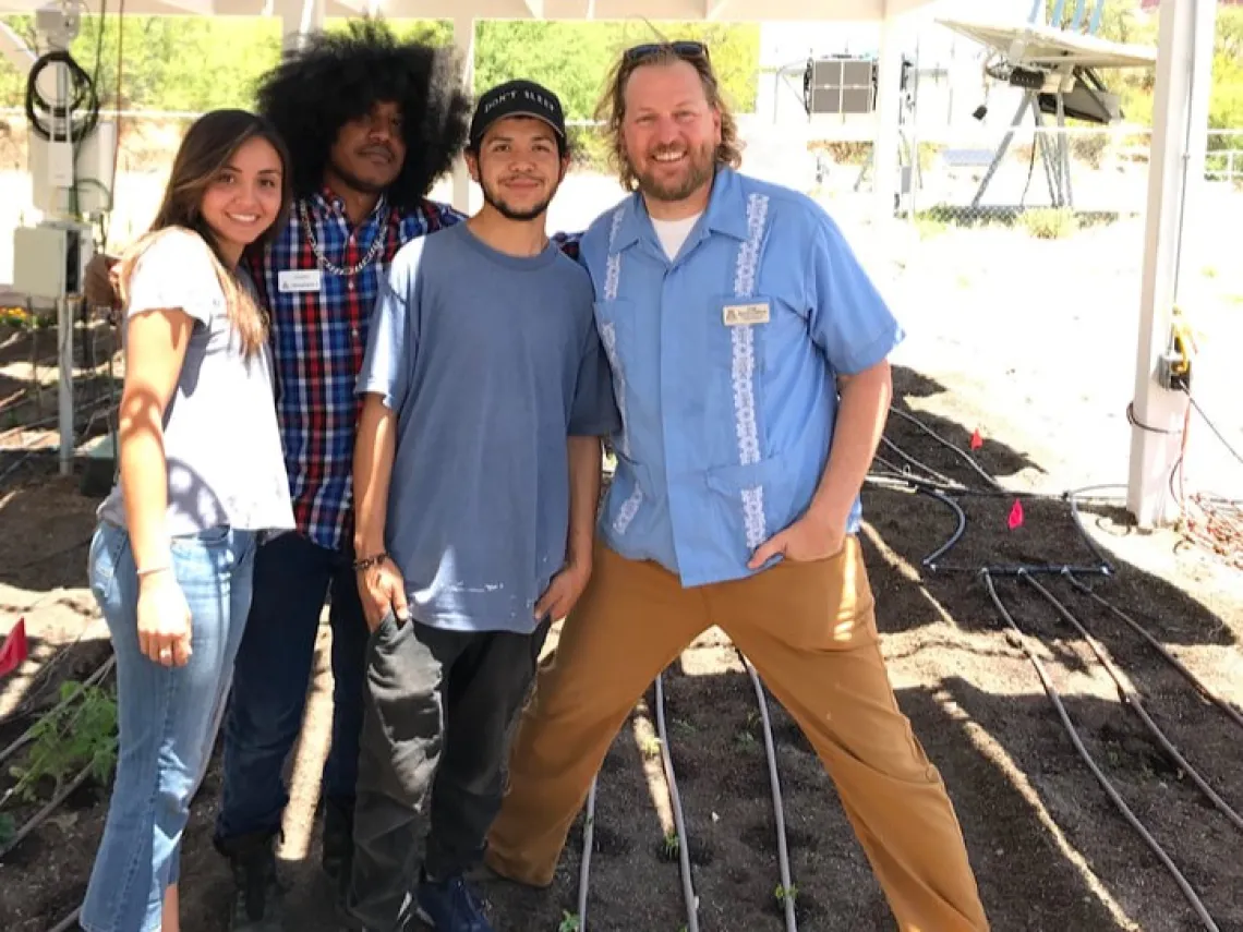 Greg Barron Gafford with three students at an agrivoltaics plot