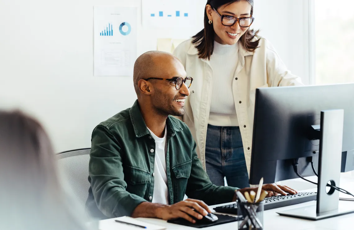 a man and a woman with glasses in front of a computer screen