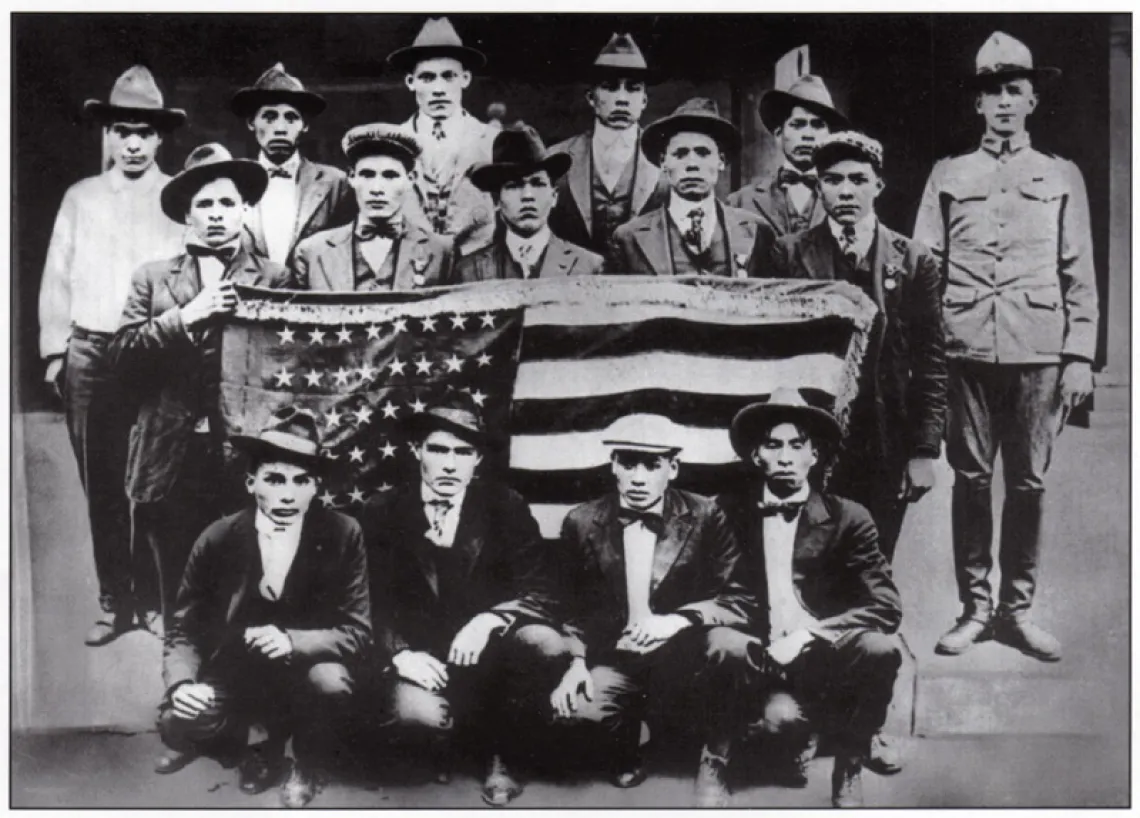 Black and white photo of 15 men during WWI timeframe, holding an American flag