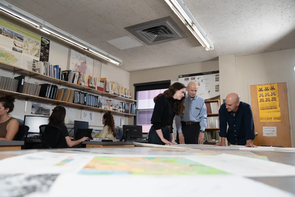 David Gilman Romano stands at a mapping table with two students