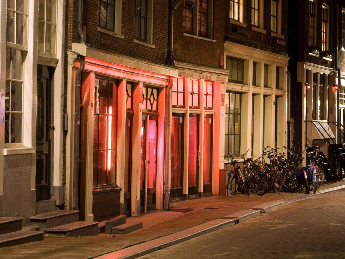 A street in Amsterdam at night, with red lights on in several doorways