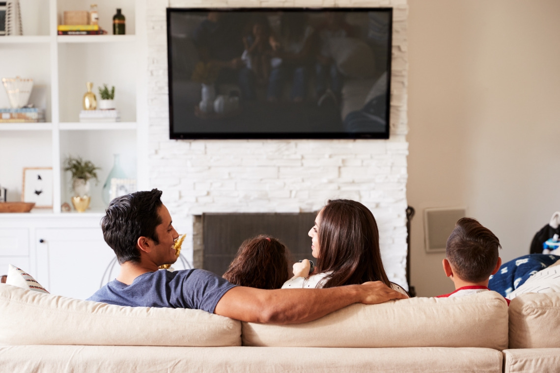 Latino family, father, mother and two children watching TV