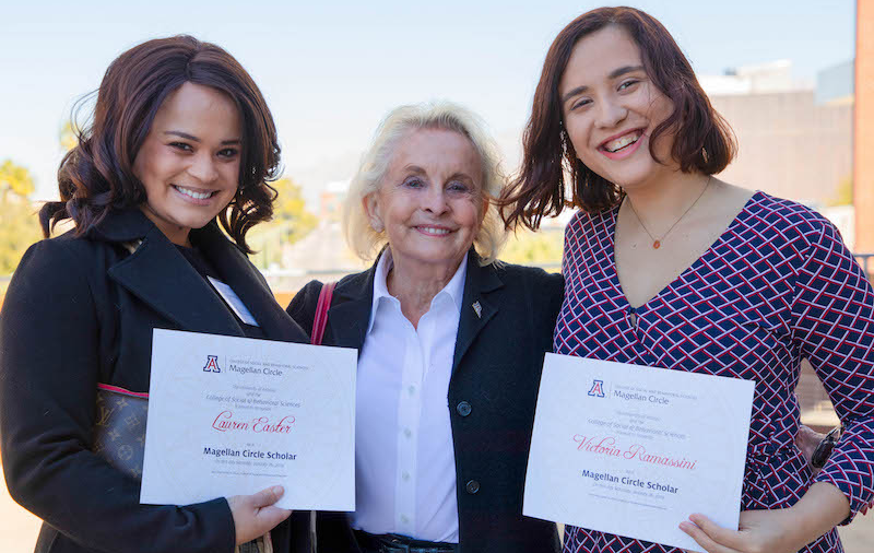 Two scholarship recipients posing with a donor.