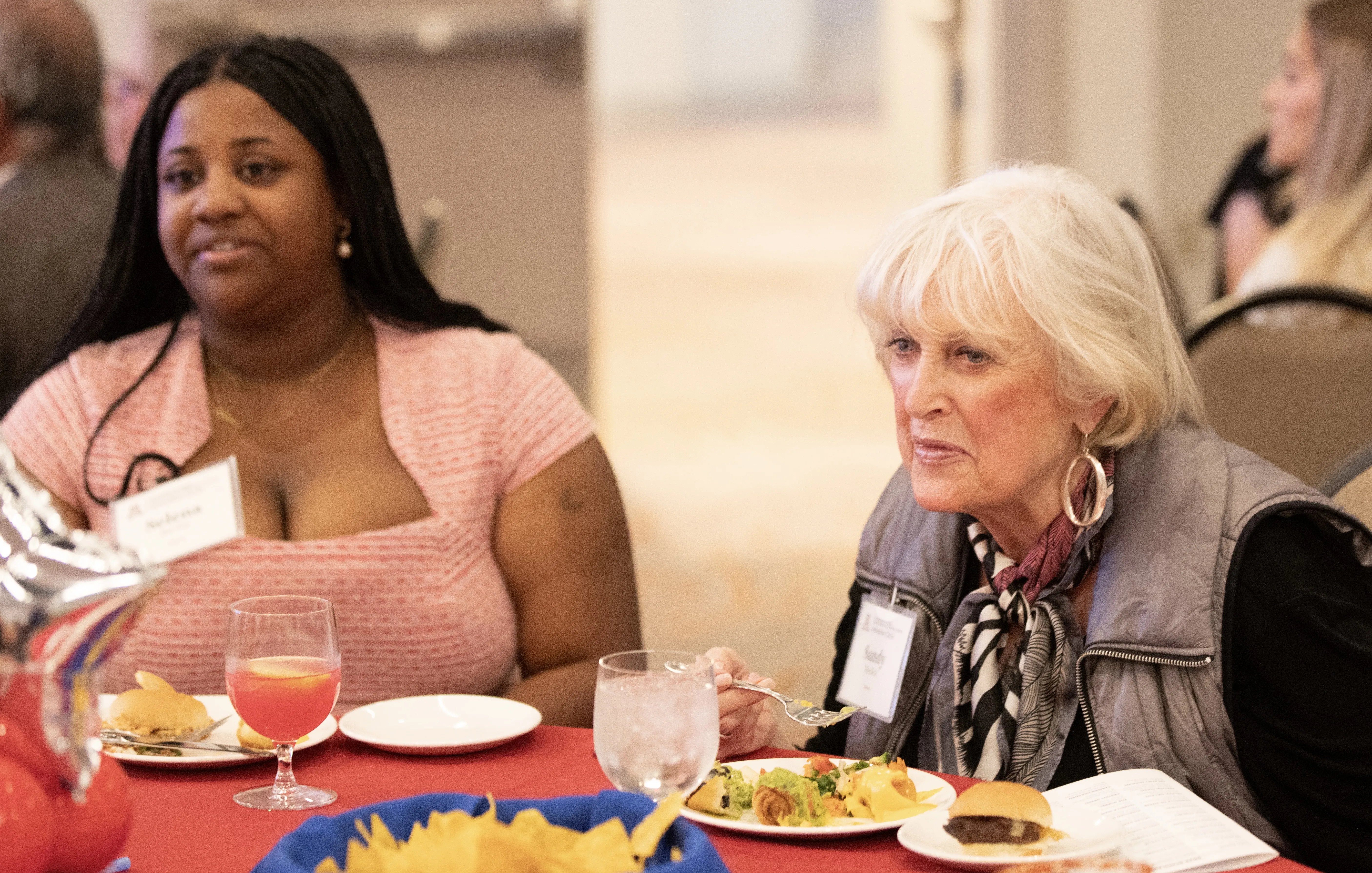 A student sits at a dinner table with her patron as they eat