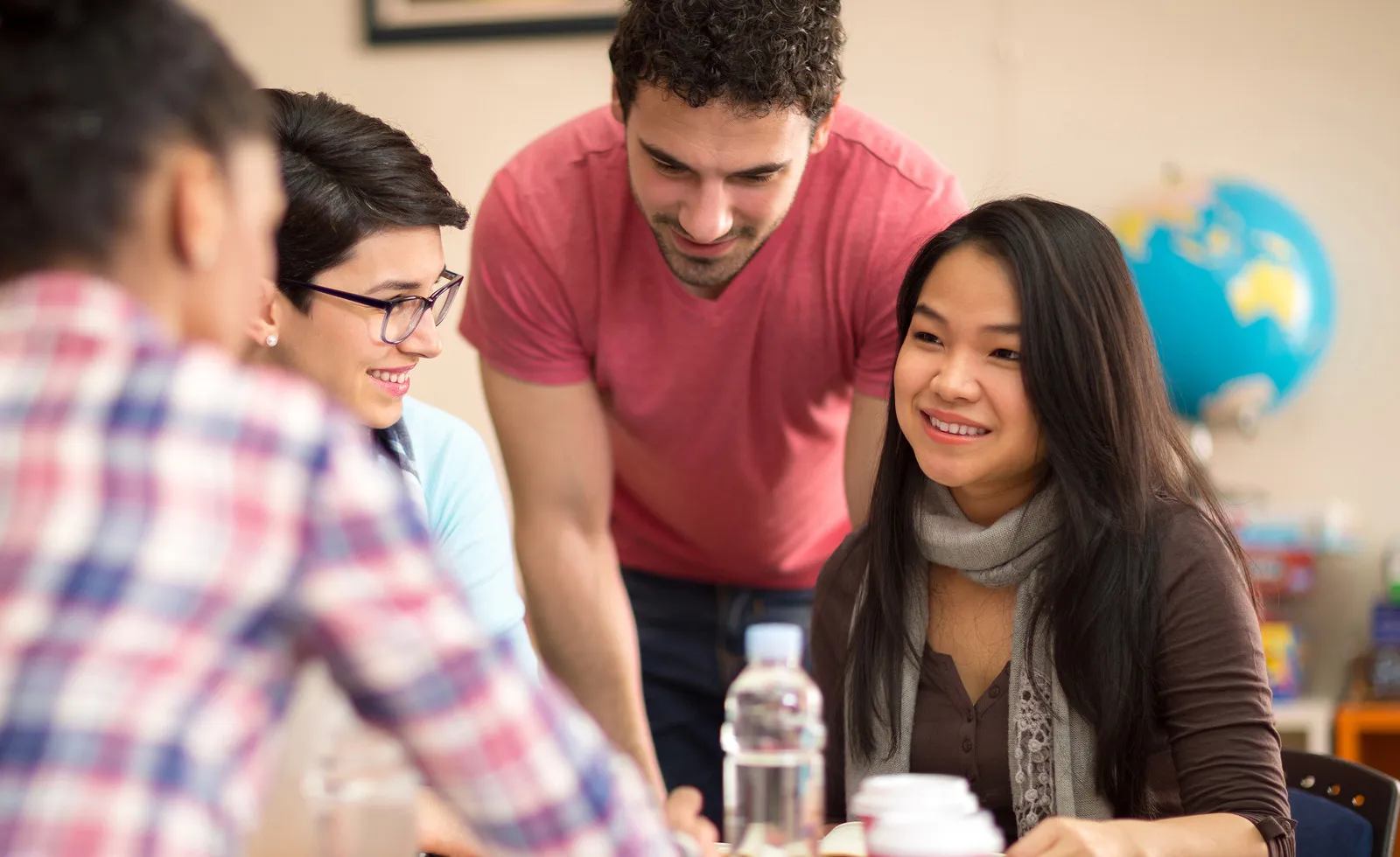 four students at a table with a globe in the background