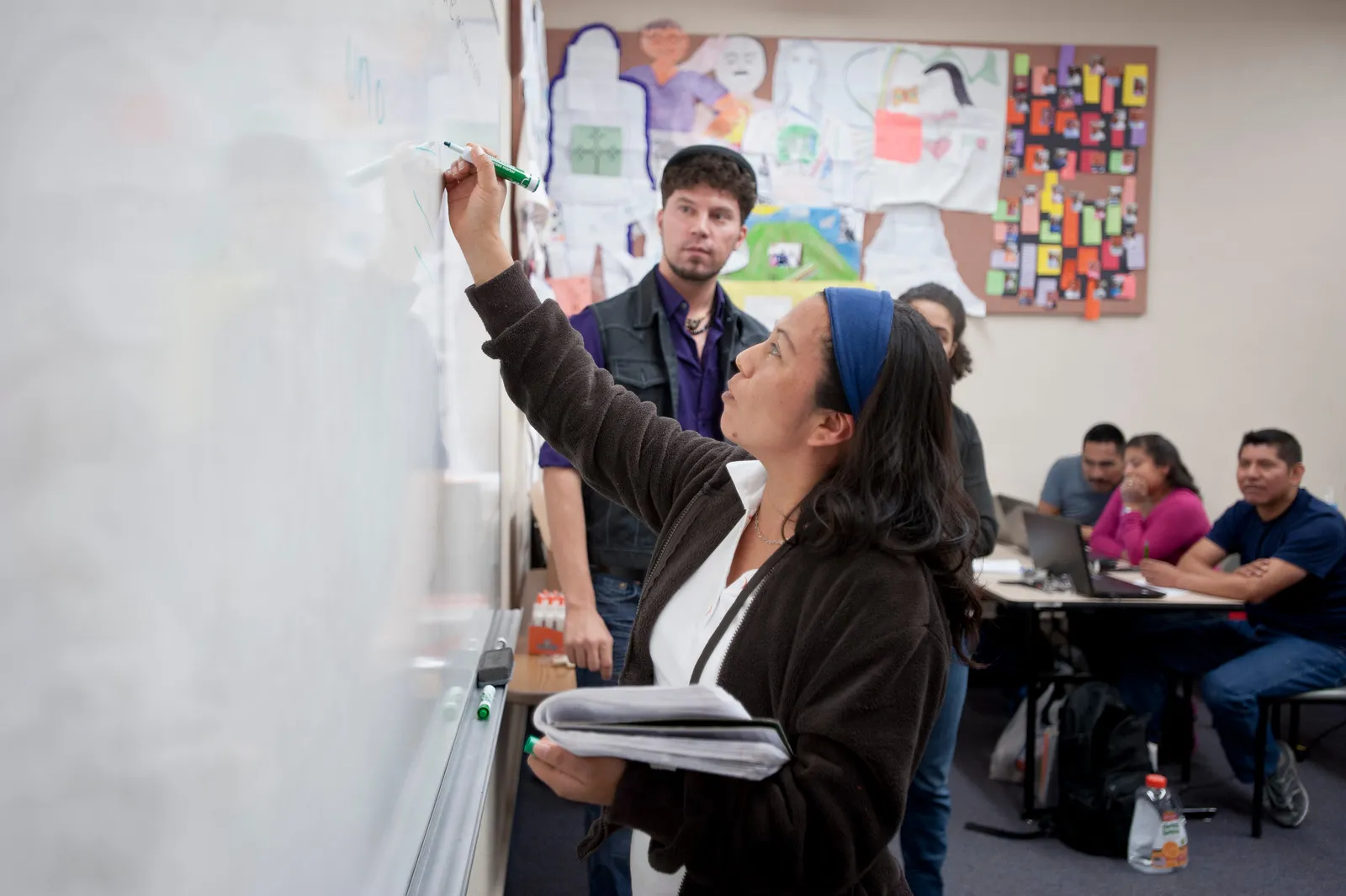 Small group of students writing at white board