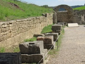 A row of ancient stone monuments lined up next to a stone wall