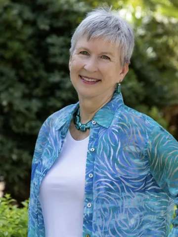 Woman with short hair and blue blouse, standing outside