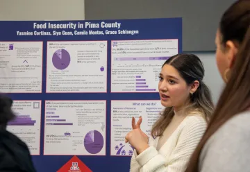 student pointing at poster related to housting insecurity