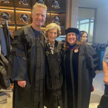 Three people standing in graduation regalia